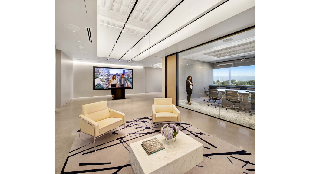 A person standing in a room with a large screen and chairs.