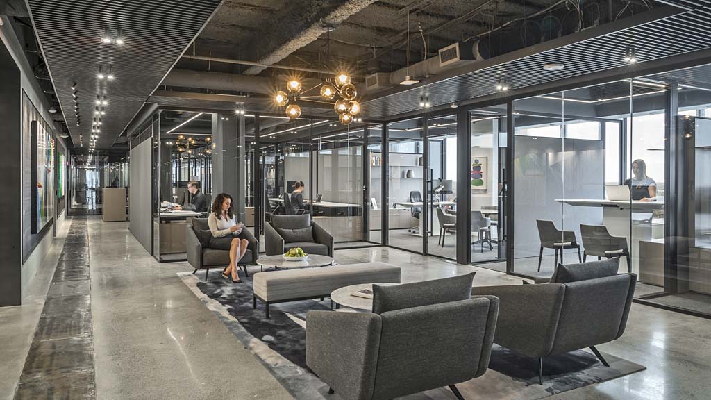 A group of people sitting at a table in a room with glass walls.