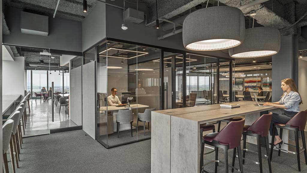 A couple of people sitting at a table in a room with a large ceiling and windows.