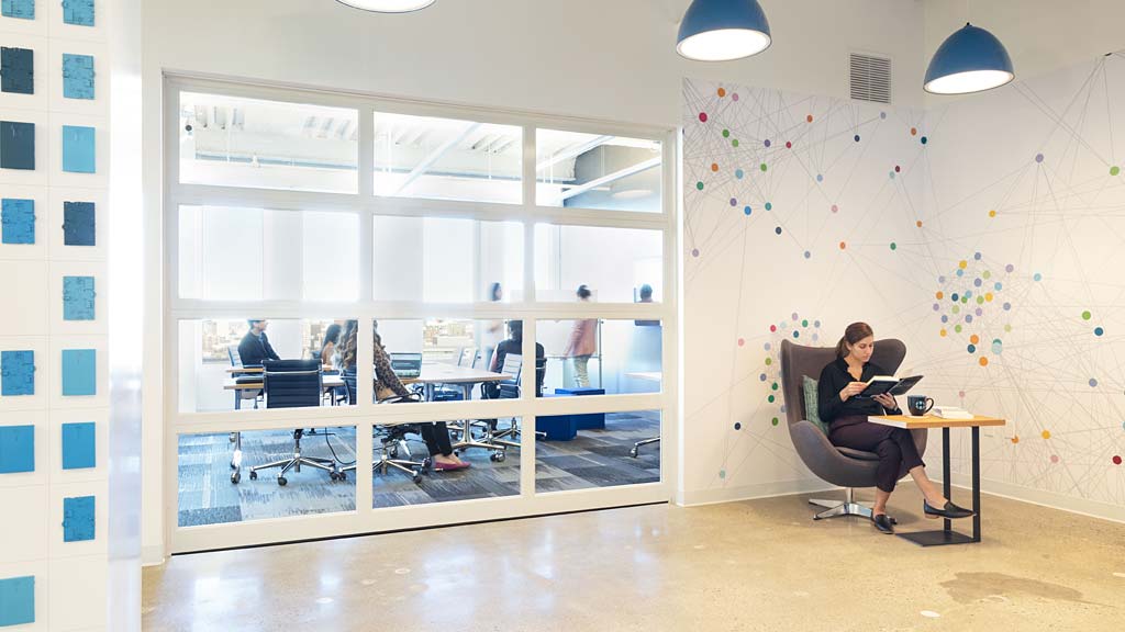 A person sitting at a desk in a room with a large window.
