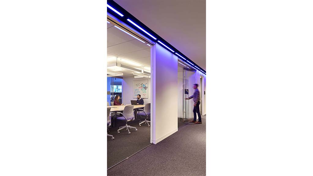 A person standing in front of a table with a white wall with a blue light.