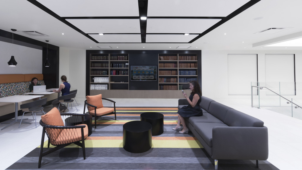 A person sitting on a couch in a room with a table and chairs.