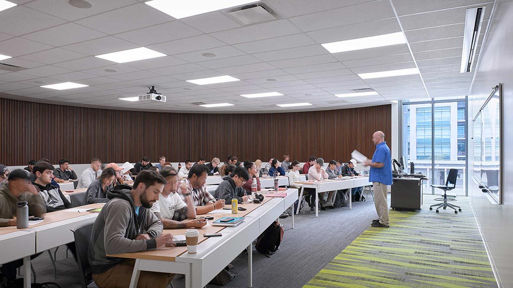 A person standing in front of a group of people sitting at tables.