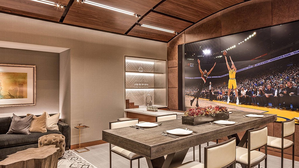 A room with a large stage and a large table with chairs and a group of people in it.