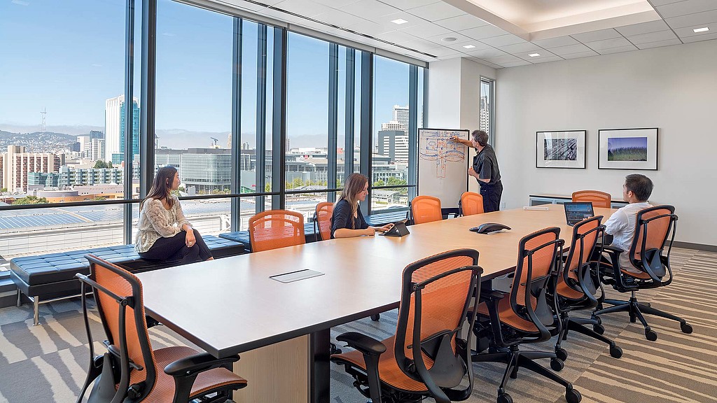 A group of people sitting around a table with a view of a city.