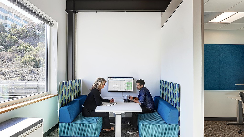 A man and a woman sitting at a table with a computer.