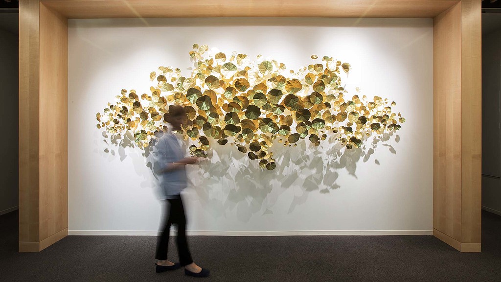 A person standing in front of a wall with flowers on it.