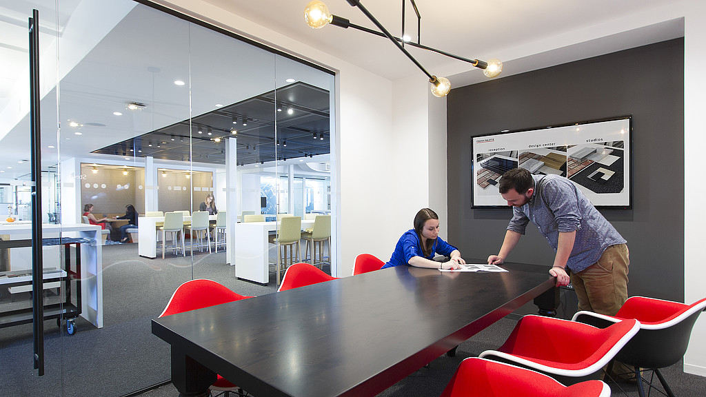 A man and a woman looking at a paper on a table.