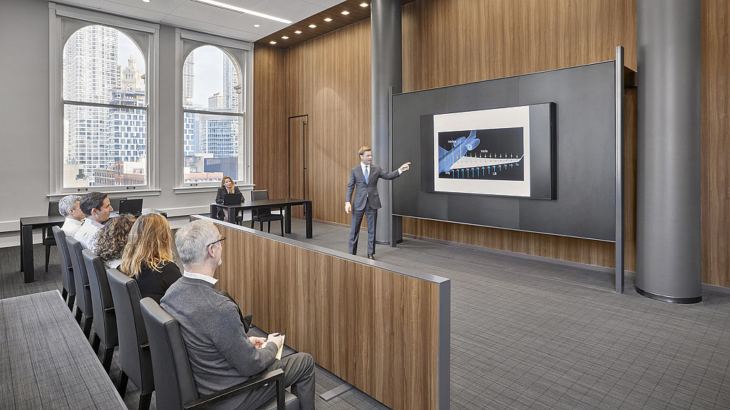 A man points at a digital screen in front of a mock courtroom inside the Chicago offices of Bartlit Beck Herman Palenchar & Scott.