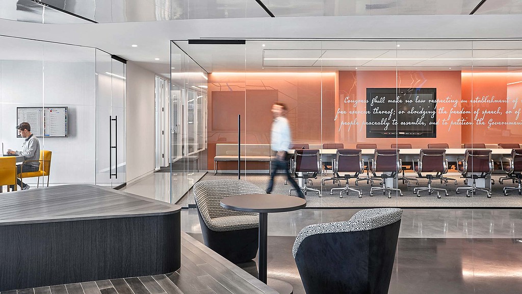 A person walking in a room with chairs and tables.