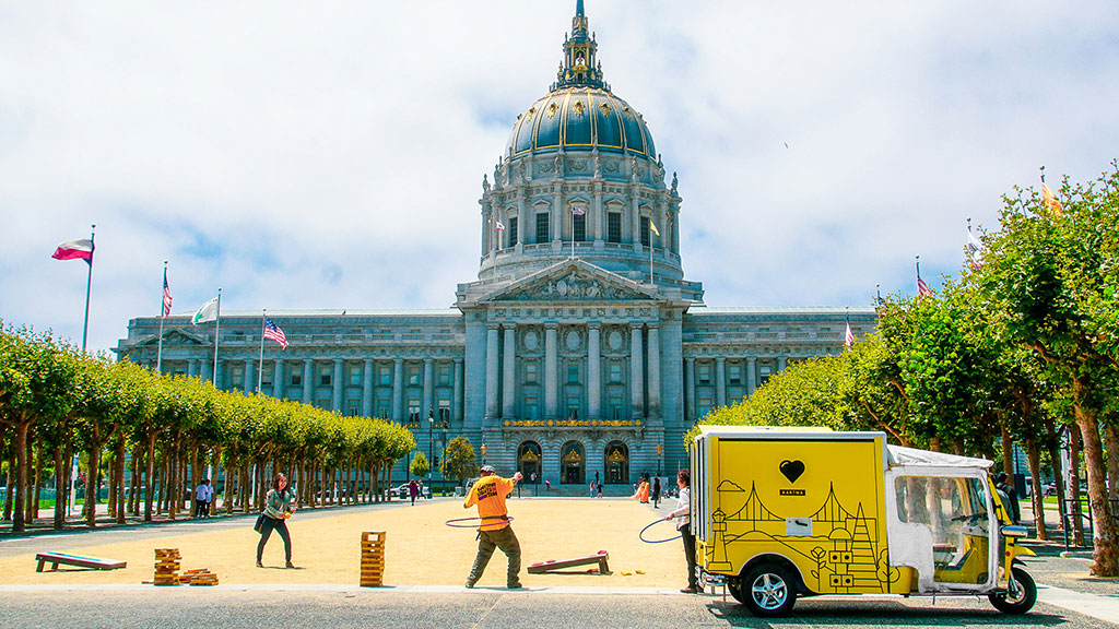 A yellow truck parked in front of a large building.
