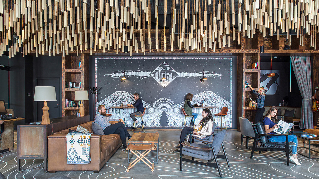 A group of people sitting in chairs in a room with a large screen.