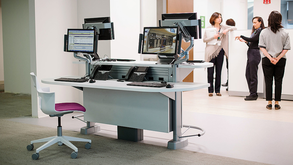 A group of women standing in front of a desk with computers.