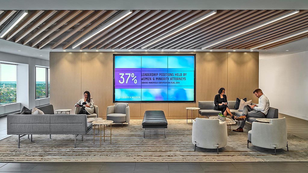 A group of people sitting in a room with a large screen.