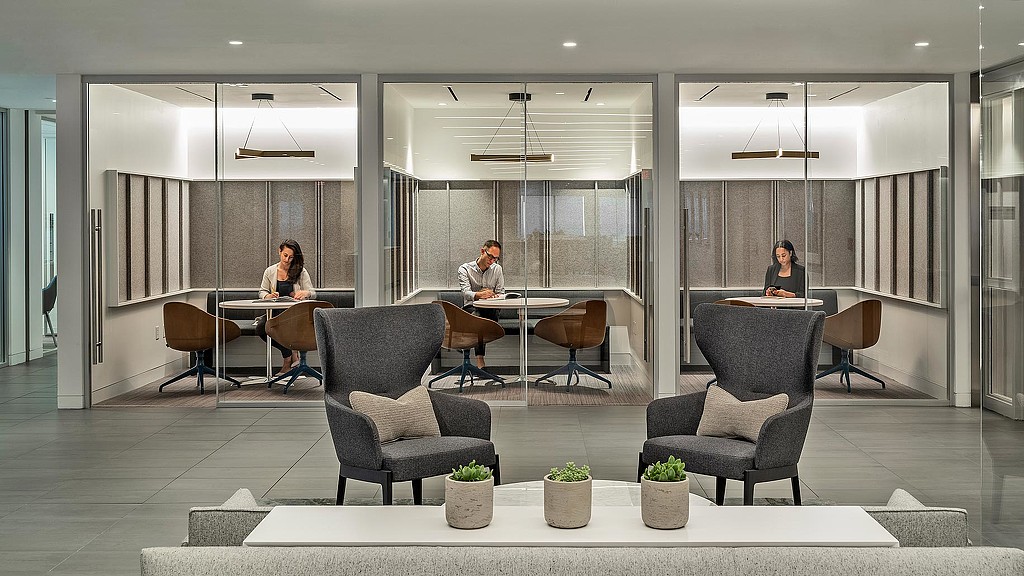 A group of people sitting at a table in a room with a large glass wall.