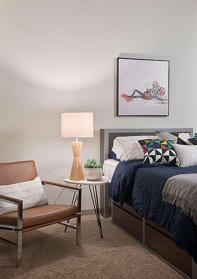 A bedroom with a bed and a chair.