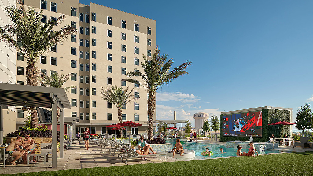 A group of people in a pool by a large building.