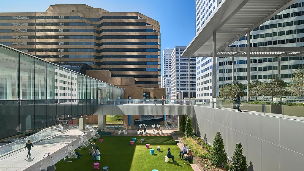 A group of people sitting on a lawn in front of a building.