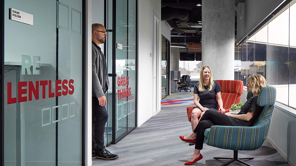 A man standing next to a woman sitting on a chair.