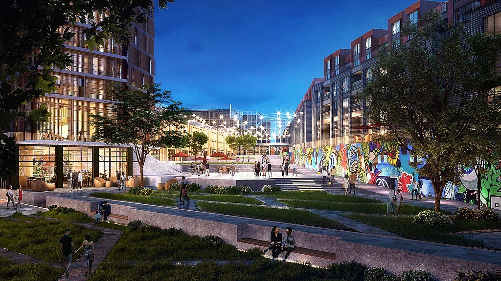 A group of people walking around a park in front of a building.