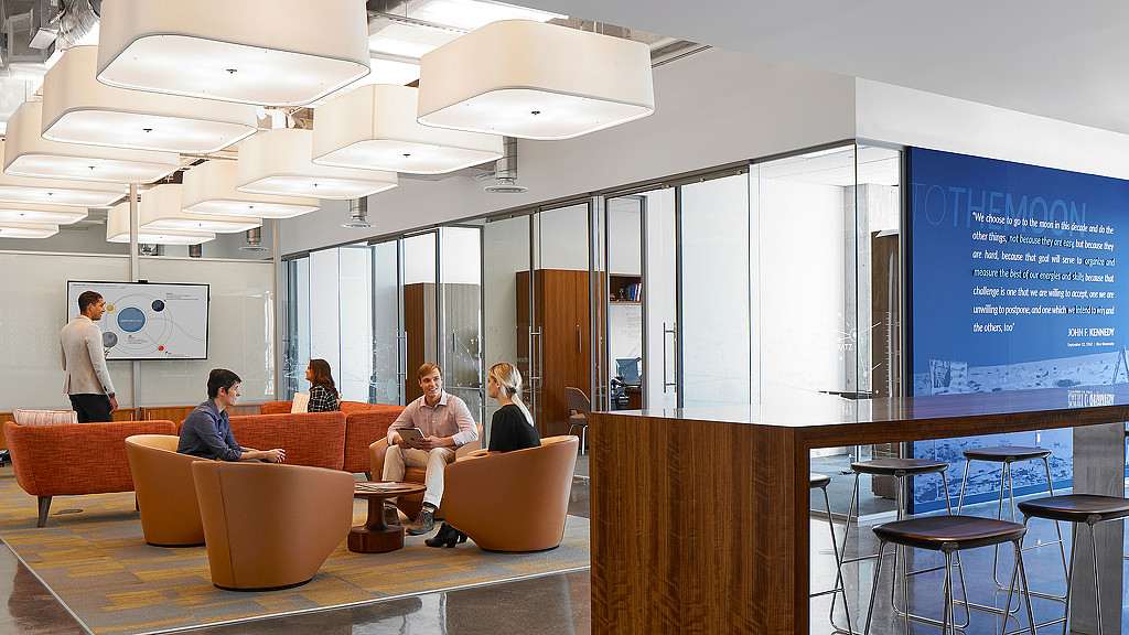A group of people sitting in a room with a large screen.