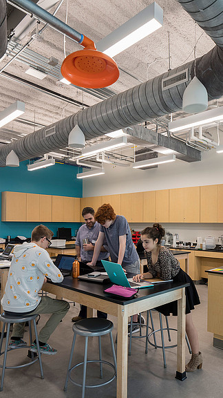 A group of people sitting at a table with a laptop.
