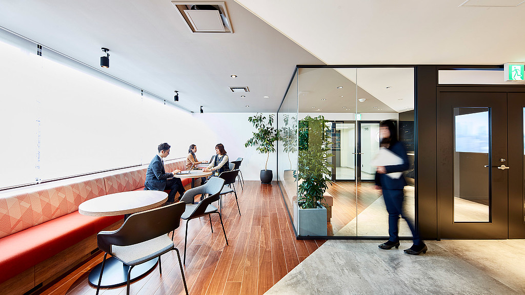 A group of people sitting at a table in a room with a wood floor and a wood floor.