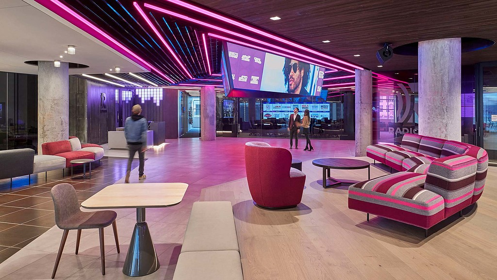 A room with red chairs and a large screen.