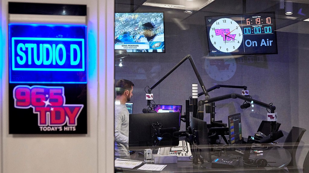 A person standing in front of a desk with a computer and a microphone.