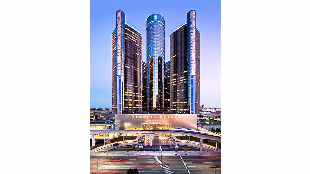 A group of tall buildings with Renaissance Center in the background.