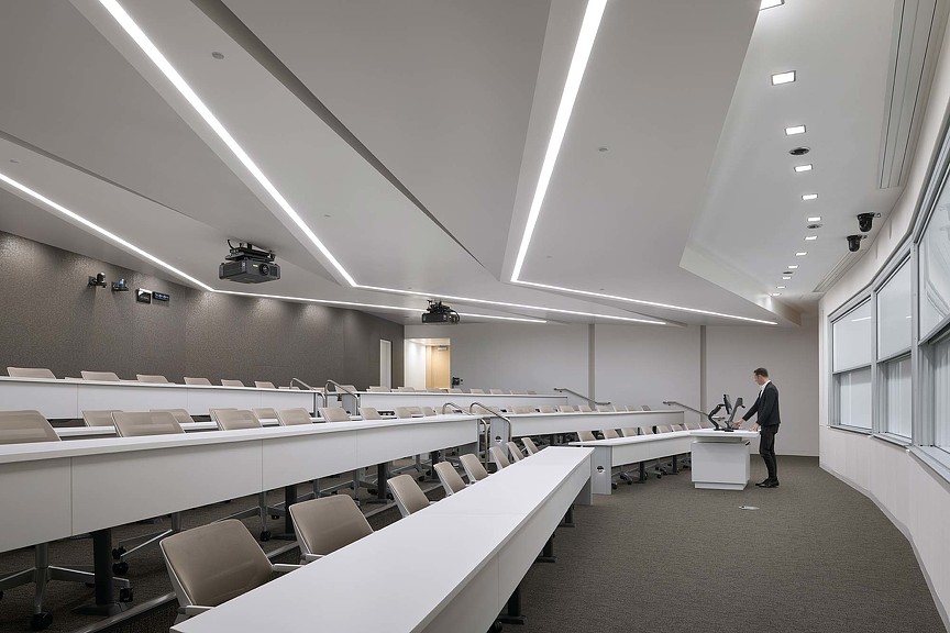A person standing in a room with white tables and chairs.