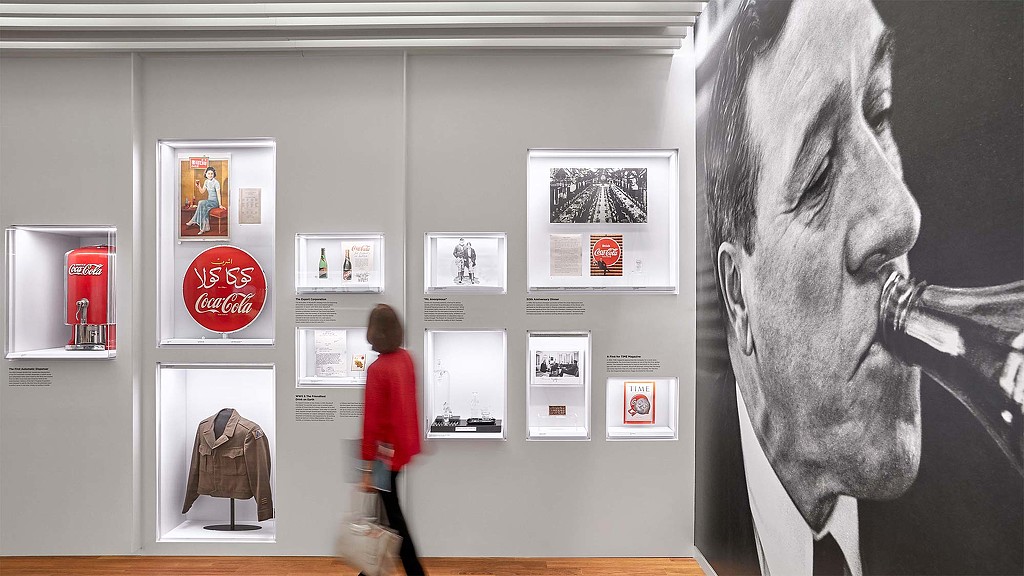 A person looking at a wall with pictures on it.