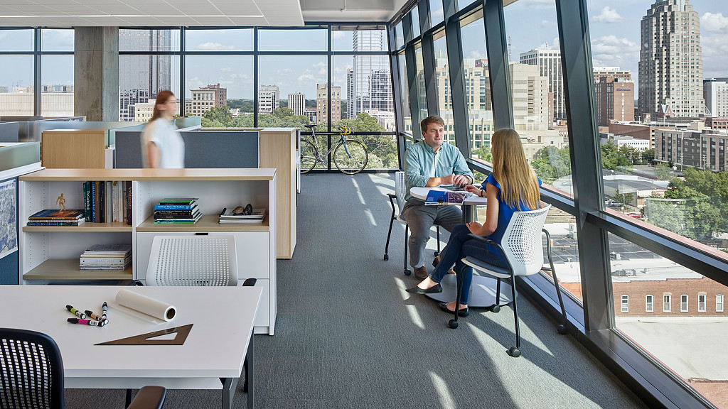 A group of people sitting at a table in a room with large windows.