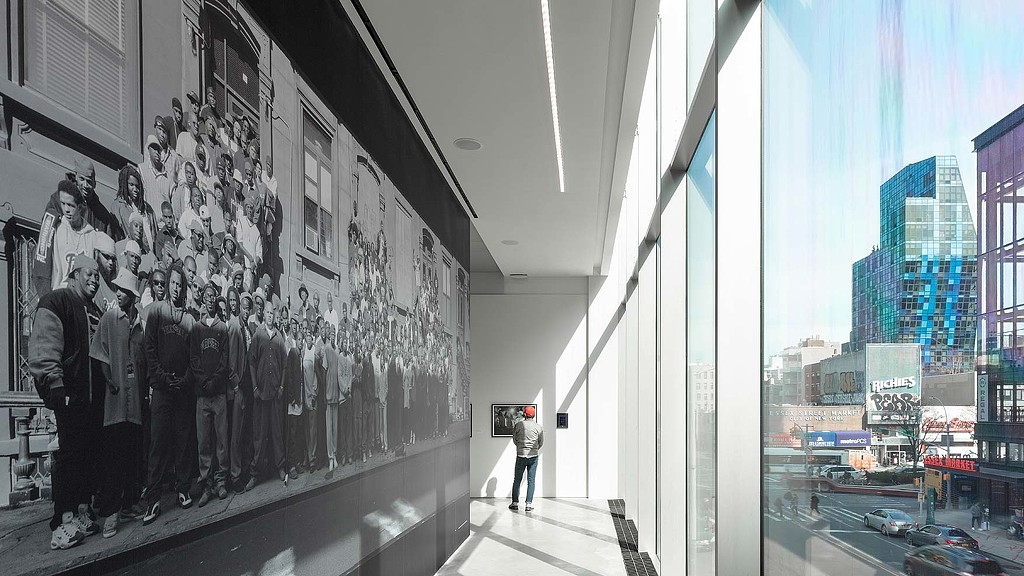 A person standing next to a wall with a mural of people.