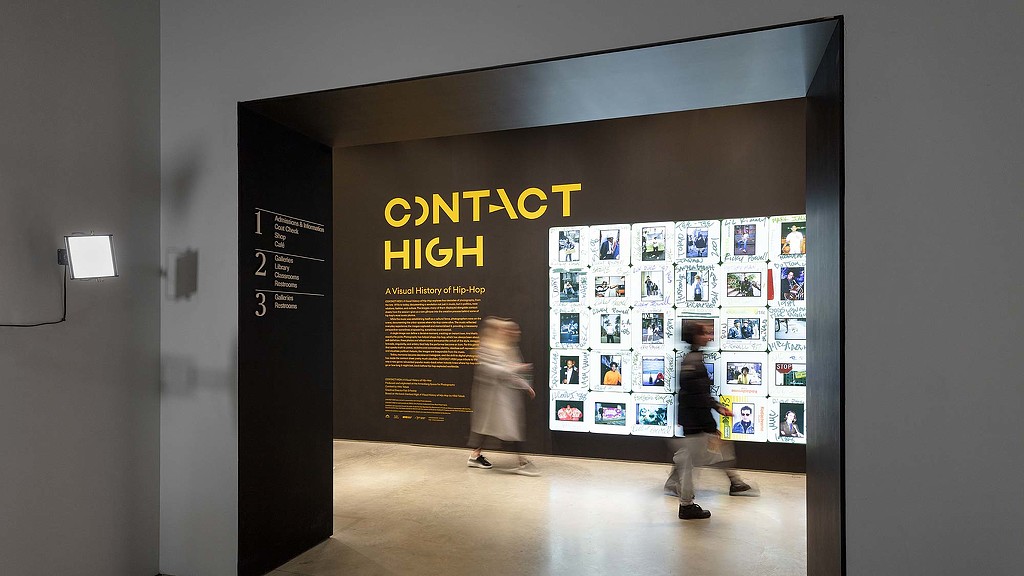 A man and woman walking through a building with a large poster.