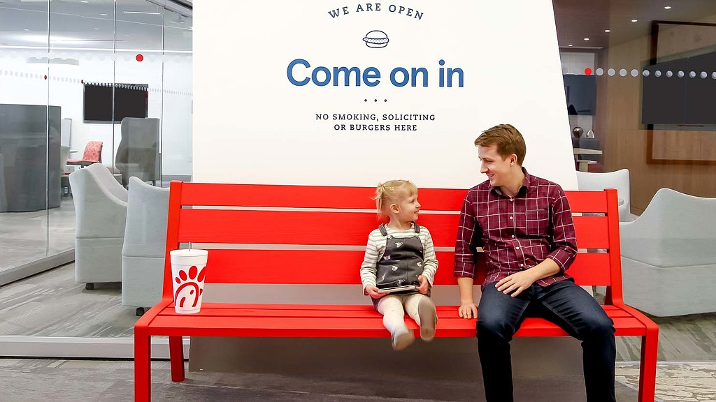 A person and a child sitting on a red bench.