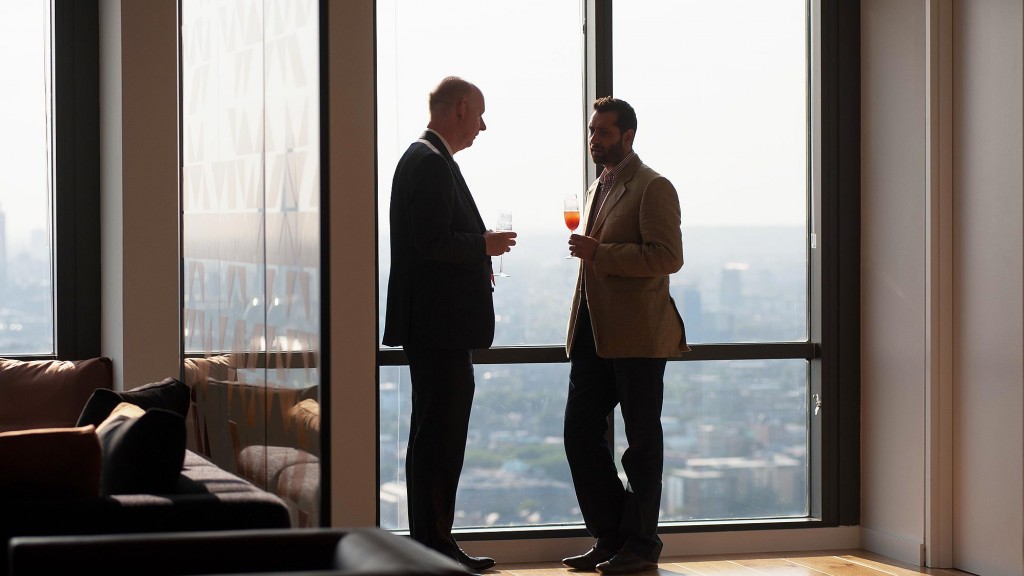 A couple of men standing in a room with a large window.