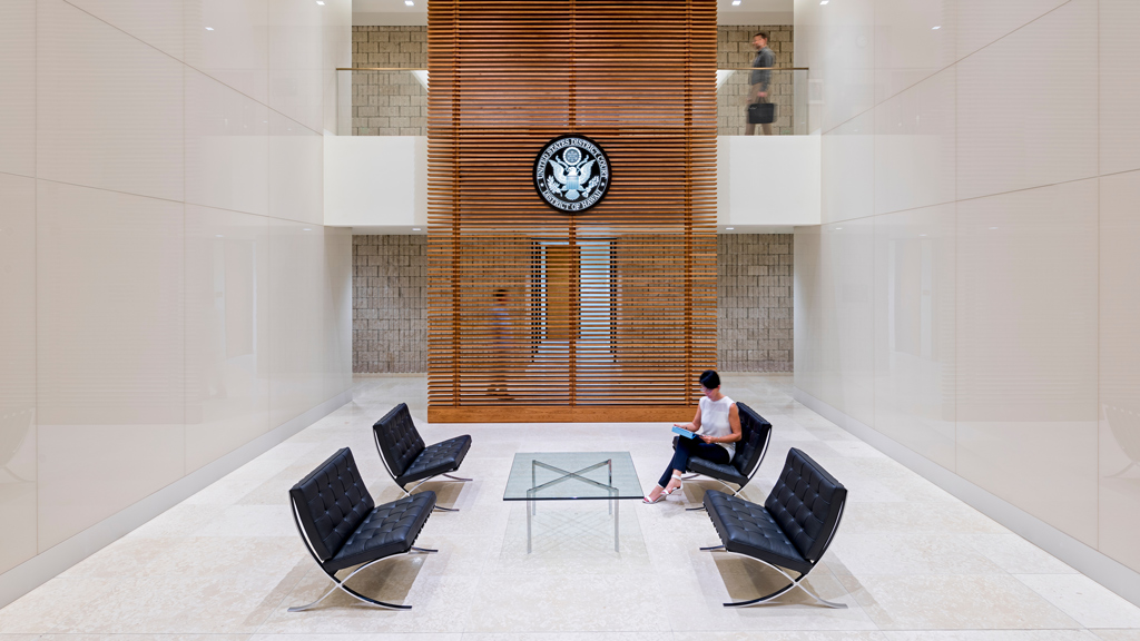 A person sitting in a room with a clock on the wall.