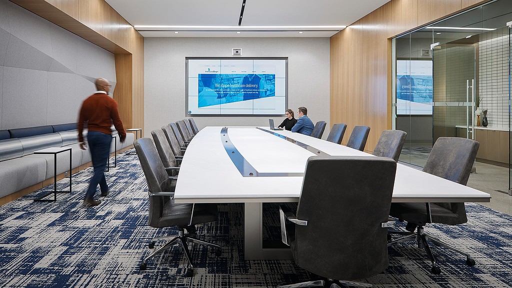 A person standing next to a table with chairs and a screen.