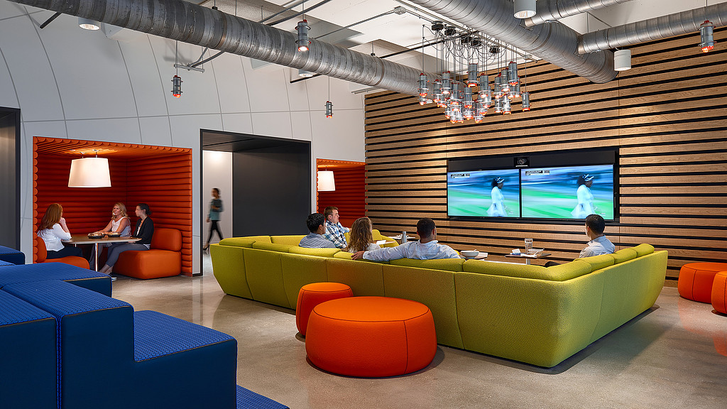 A group of people sitting on a couch in a room with a large screen.