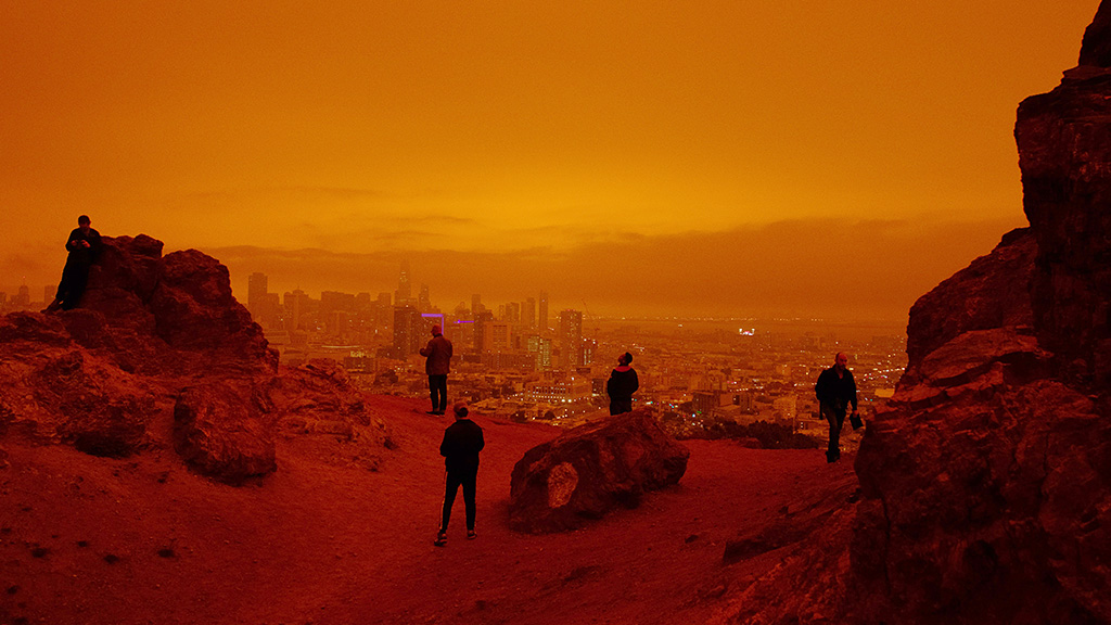 A group of people standing on a rocky hill overlooking a city.