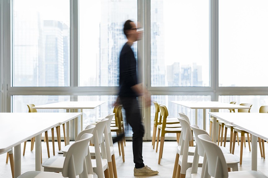 A person standing in a room with tables and chairs.
