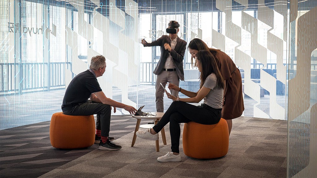 A group of people sitting on stools in front of a window.