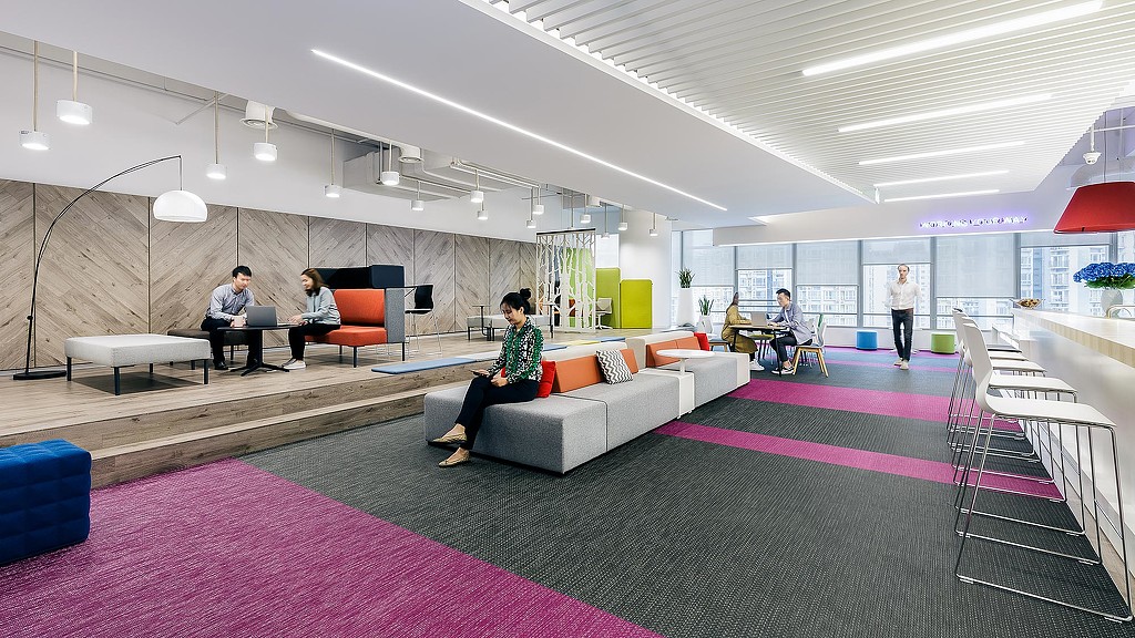 A group of people sitting in a room with a large white couch.