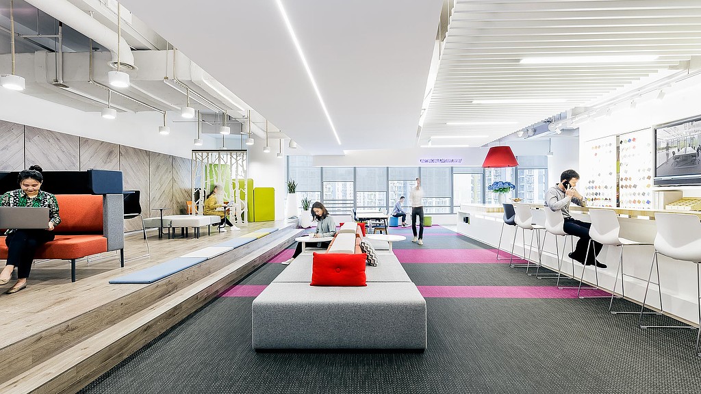 A group of people sitting in a room with a large pink and white carpet.