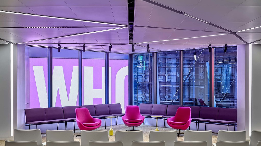 A room with purple chairs and a table with a large window.