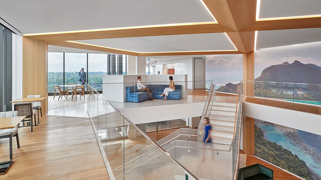 A room with a glass floor and a large glass wall with people sitting on it.