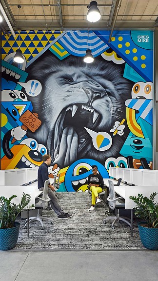 A person sitting on a bench in front of a mural.