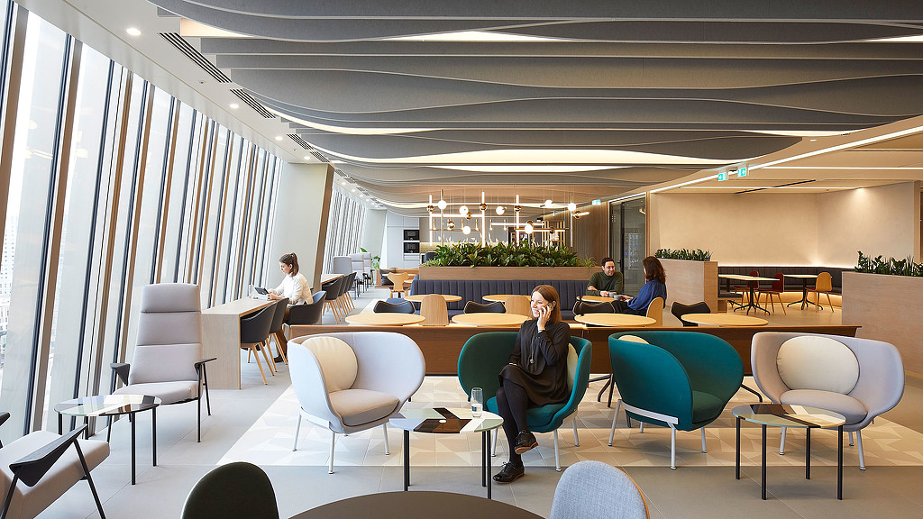 A group of people sitting in a room with chairs and tables.