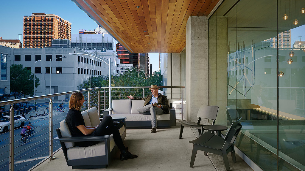 A man and woman sitting on a bench in front of a building.